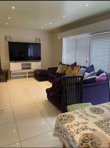 a living room with a couch and a flat screen tv at Smart Large Room with disabled facilities Idealy Located near Doncaster - Rotherham -Sheffield in Rotherham