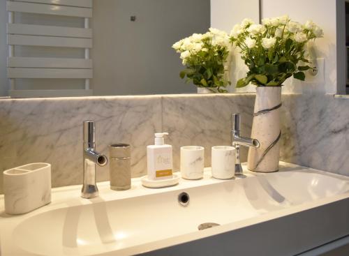 La salle de bains est pourvue d'un lavabo et d'un vase de fleurs. dans l'établissement Montmartre, à Paris