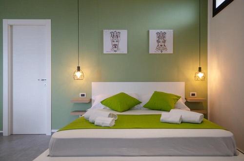 een slaapkamer met een groot bed met groene muren bij Sunrise Luxury Apartments in Cassibile