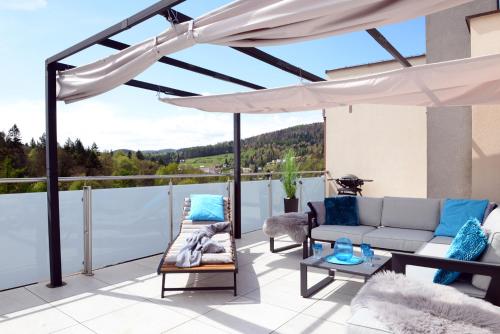 a patio with a couch and umbrella on a balcony at Apartamenty Kora in Krynica Zdrój