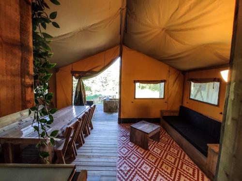 a room with a couch and tables in a tent at Camping la Grangeonne in Esparron-de-Verdon