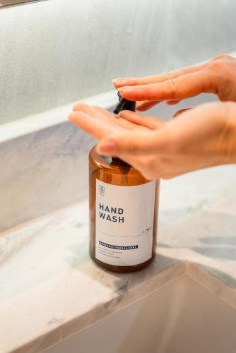 a hand reaching for a jar of hand wasatch at THEA Private Suites by TH District in Bangkok