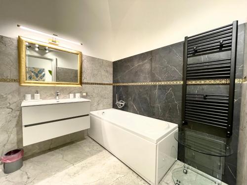 un bagno con vasca, lavandino e specchio di Nel Cuore di Palermo Isidoro Palace a Palermo