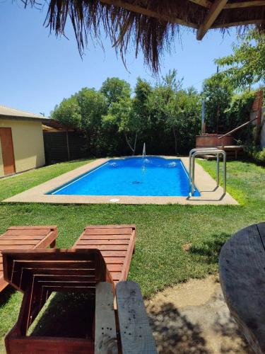 a swimming pool with two chairs and a table at Cabañas Doña Juanita in Olmué