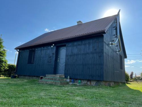 a black building with a door on a grass field at Siedlisko Glinnik in Glinnik