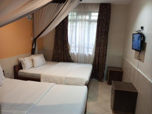 Una habitación de hotel con dos camas y un televisor. en Fourth Parklands Hotel, en Nairobi