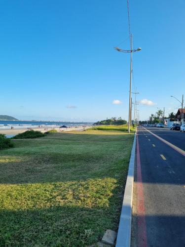 a road next to a beach with a rainbow at Canto das Ondas Apart Studios in São Francisco do Sul