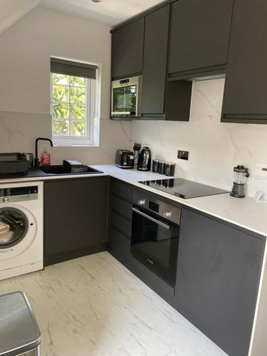 uma cozinha com armários a preto e branco e uma máquina de lavar louça em WHITEHILL STABLES em Kirknewton