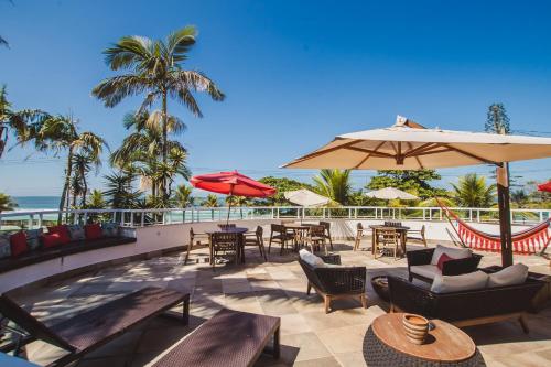 a patio with tables and chairs and an umbrella at Hotel VillaReal Guaratuba - Caieiras in Guaratuba