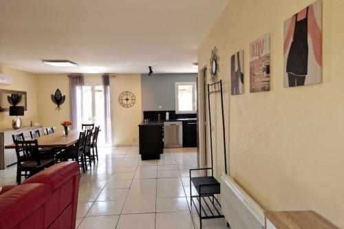 a living room and kitchen with a red couch and a table at Maison familiale in Podensac