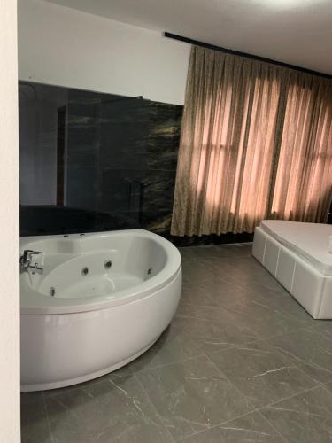 a white bath tub in a bathroom with a bed at Hotel Albatros in Prizren