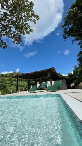 a swimming pool with chairs and a gazebo at Pousada paraíso pedra do Rodeadouro in Bonito