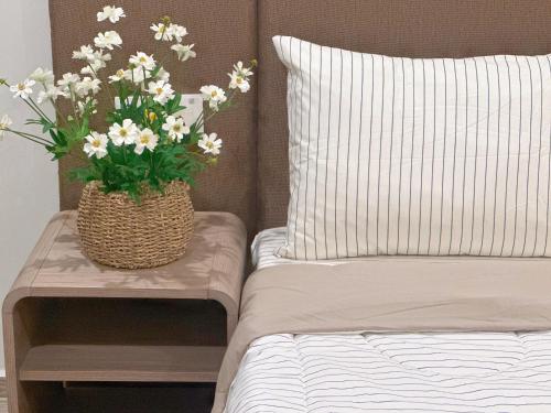 a vase of flowers sitting on a table next to a bed at The Sóng Vũng Tàu Homestay - Suri's Apartment in Vung Tau