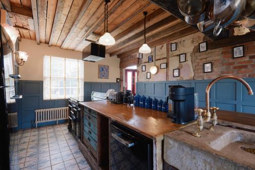 a large kitchen with blue walls and wooden ceilings at Beautiful Countryside Farmhouse in Sutton Bonington