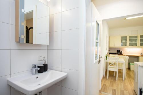 La salle de bains blanche est pourvue d'un lavabo et d'un miroir. dans l'établissement Wolfgangthal Apartments in Bad Ischl City Center am TRAUNKAi, à Bad Ischl