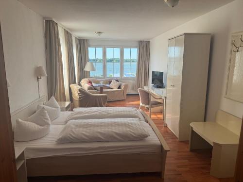 a bedroom with a bed and a living room at Hotel Perle am Bodden in Ribnitz-Damgarten