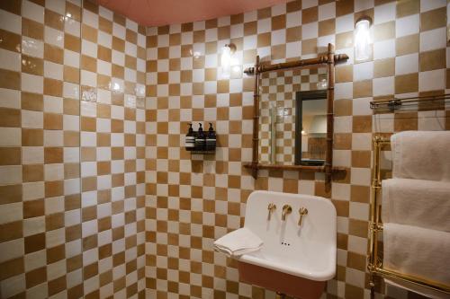 a tiled bathroom with a sink and a mirror at The Grain Store in Sutton Bonington