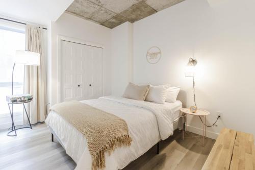 a white bedroom with a bed and a table at Northeka208 in Quebec City