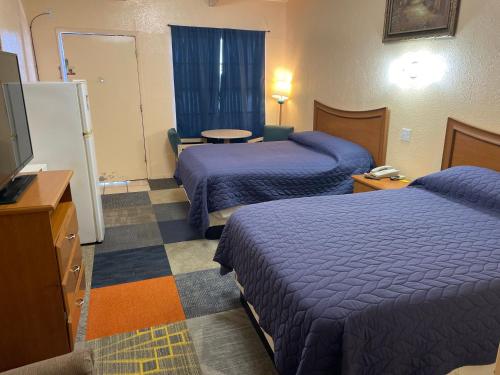 a hotel room with two beds and a flat screen tv at Relax Inn Goldthwaite in Goldthwaite