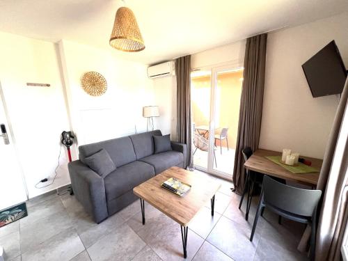 un soggiorno con divano e tavolo di Résidence hôtelière les hameaux de saint cyprien appartement 25 M2 1 chambre a Lecci