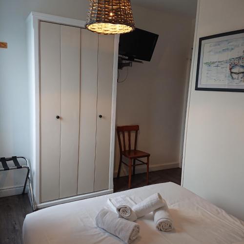 een slaapkamer met een bed met handdoeken en een kroonluchter bij Le Parc aux Huîtres in Cayeux-sur-Mer