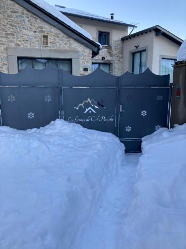 un portail bleu avec de la neige dessus devant une maison dans l'établissement Les Fermes de Cal Panche : Le Corps de Ferme, aux Angles