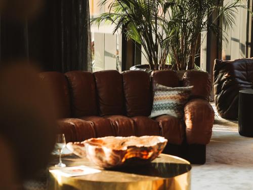 a brown leather couch in a living room with a table at La Butte aux Bois a Small Luxury Hotel of the World in Lanaken