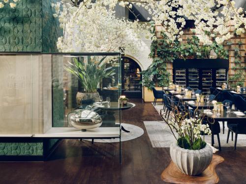 a restaurant with tables and chairs and flowers at La Butte aux Bois a Small Luxury Hotel of the World in Lanaken