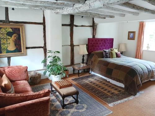 um quarto com uma cama e uma cadeira em Michaelmas Cottage Upavon em Upavon