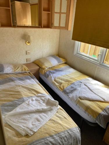 2 Betten in einem Zimmer mit Fenster in der Unterkunft Pen llyn holiday cottages and caravan in Newborough