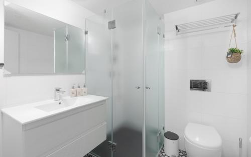 a white bathroom with a sink and a shower at סוויטות עם נוף וצמודות לים במתחם SeaSide היוקרתי עם בריכה in Eilat