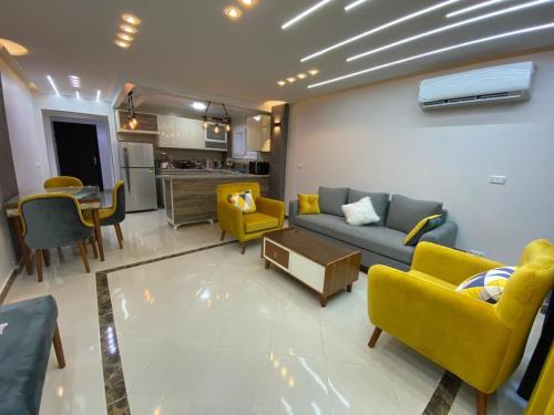 a living room with yellow chairs and a couch at شاليهات مارينا دلتا ولاجونز in Al Ḩammād