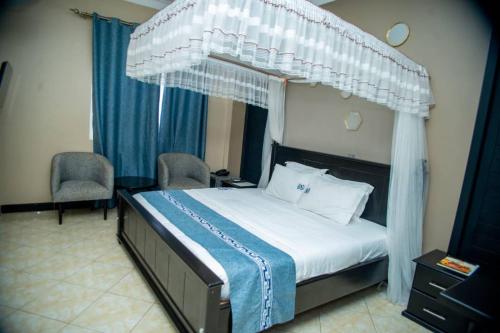 a bedroom with a canopy bed with two chairs at Grady Hotel in Bulindo