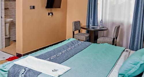Zimmer mit einem Bett, einem Tisch und Stühlen in der Unterkunft Grady Hotel in Bulindo