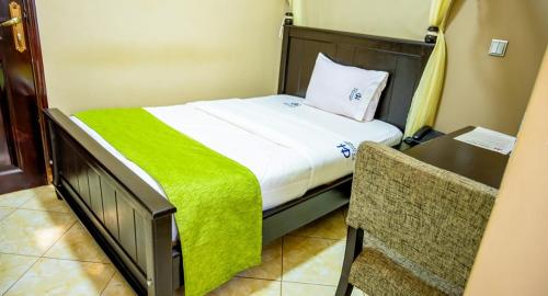 ein Schlafzimmer mit einem Bett mit einer grünen Decke darauf in der Unterkunft Grady Hotel in Bulindo