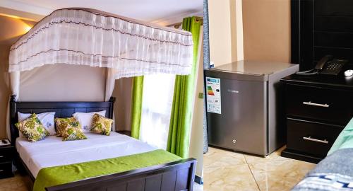 Schlafzimmer mit Himmelbett und Telefon in der Unterkunft Grady Hotel in Bulindo