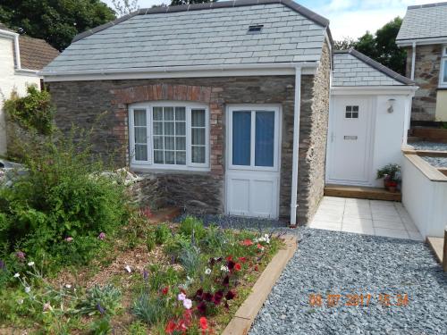 a brick house with a white door and a garden at Rose's Cottage in Gorran Haven