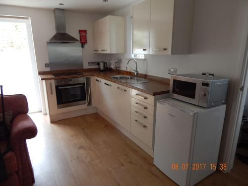 a kitchen with white cabinets and a sink at Rose's Cottage in Gorran Haven