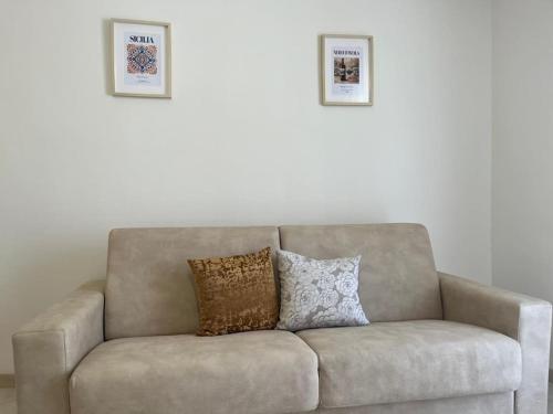 a couch with two pillows sitting under two pictures at Don Pippinu Home - Casa vacanze in Rosolini