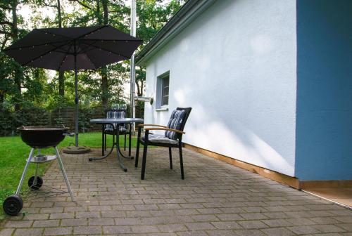 a patio with two chairs and an umbrella and a grill at Ferienhaus Strandmuschel am Ostseestrand Zierow in Zierow