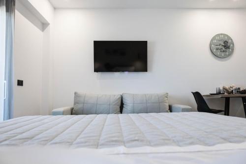 a white bedroom with a bed and a tv on the wall at Aegeans Eye in Azolimnos
