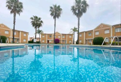 a large swimming pool with palm trees and buildings at Casa Laya en Oliva Nova in Oliva