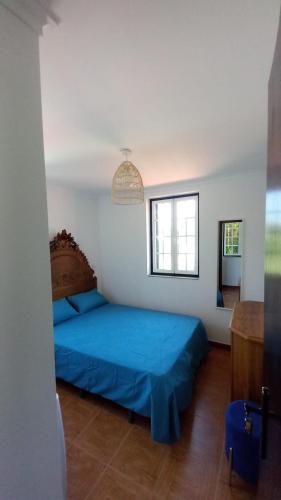 a bedroom with a blue bed and a window at As Casinhas de Santo Ovidio in Fafe