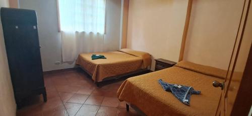 a small room with two beds and a window at Hostal Dulces Sueños in Panajachel