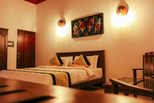 a bedroom with a bed and a painting on the wall at Xotic Resort in Kurunegala