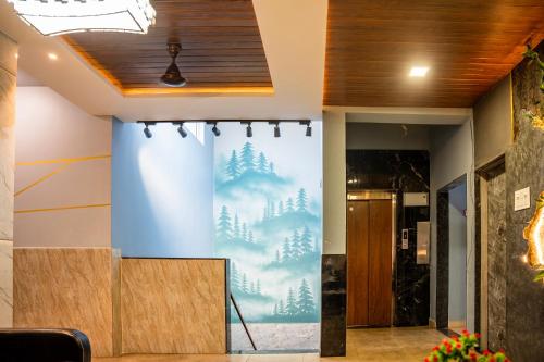 a wall in a room with a mural of trees at Hotel Happy Stay Kolhapur 2 km from kolhapur airport in Kolhapur