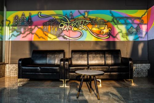 a black leather couch in front of a wall with graffiti at Hotel Happy Stay Kolhapur 2 km from kolhapur airport in Kolhapur