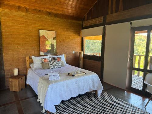 a bedroom with a bed with a white bedspread at Chale com hidro na Serra da Mantiqueira in Sapucaí-Mirim