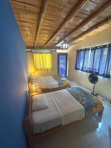 two twin beds in a room with windows at Punta Pacífico Bungalows Máncora in Máncora