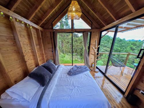 uma cama num quarto com uma grande janela em Rùstico Glamping em Santa Elena